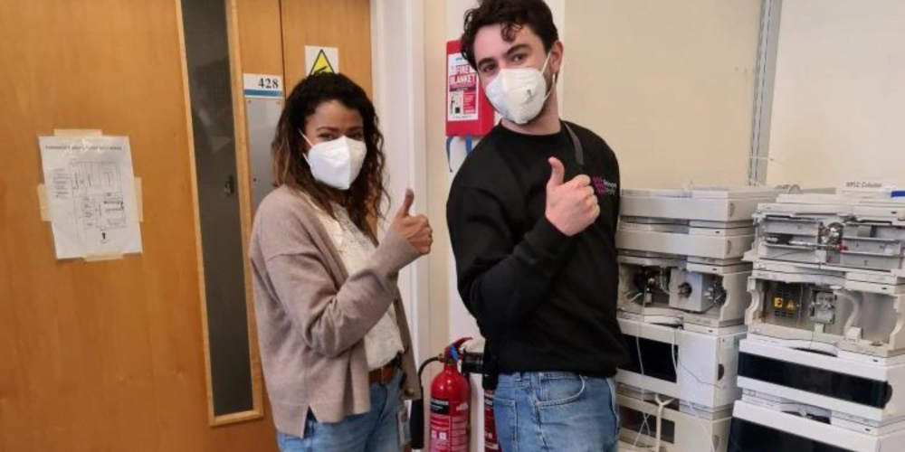 Two people standing with HPLC laboratory equipment