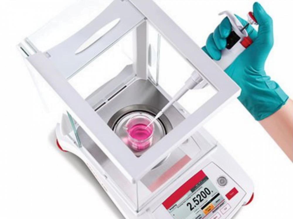 Lab balance with hand pipetting pink liquid