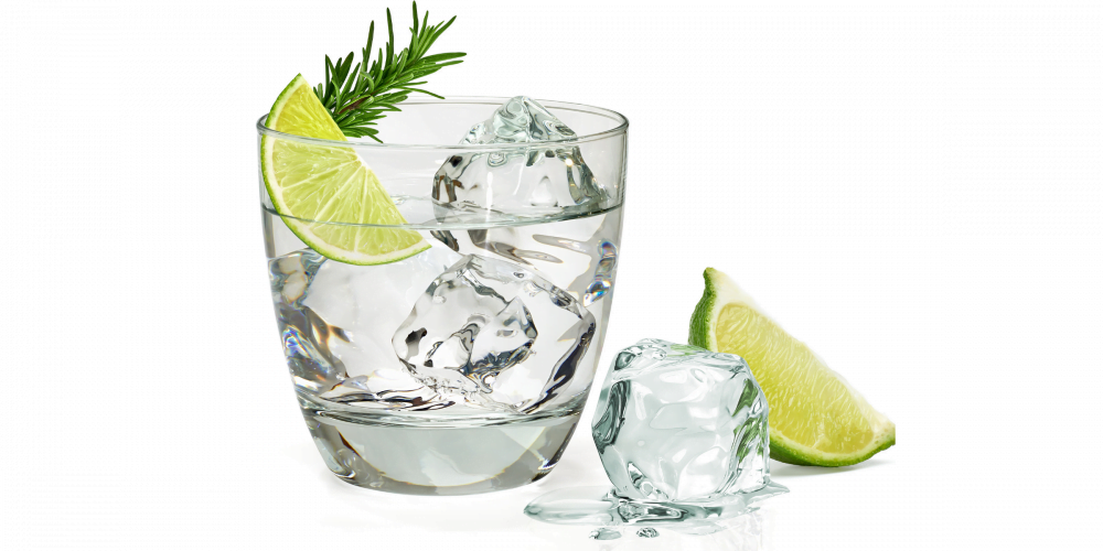 Glass of clear gin with ice cubes and lime wedges