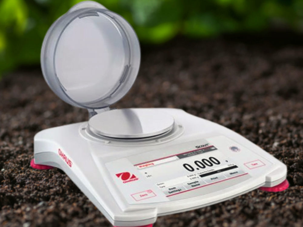 Ohaus portable scientific balance with soil in background
