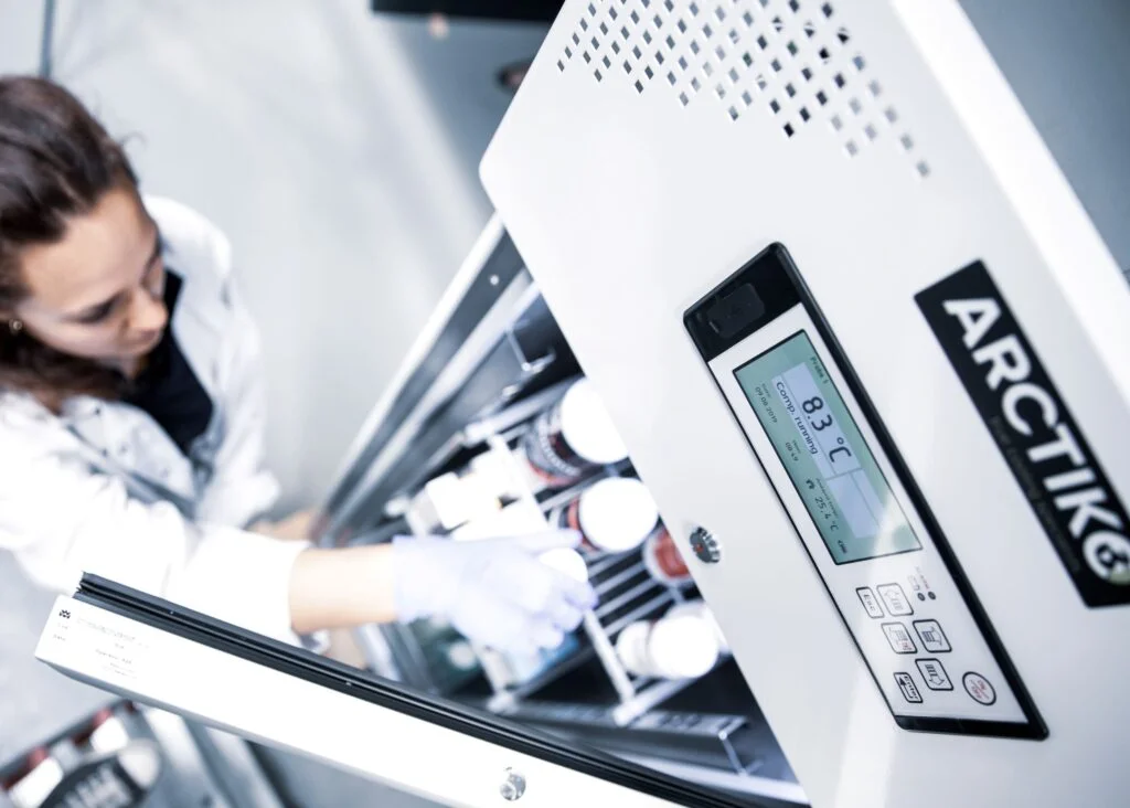 Scientist placing sample into laboratory refrigerator