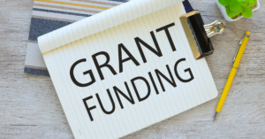 Notebook on a desk with the words grant funding printed in large letters